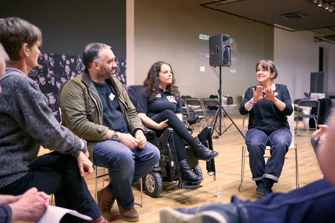 Inner Circle a group of disabled artists with an industry guest are looking towards the BSL interpreter signing